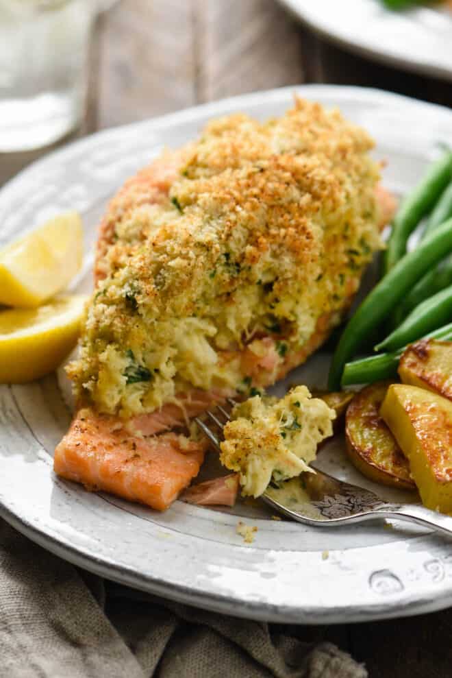 Closeup on piece of crab stuffed salmon topped with breadcrumbs, with fork taking a piece.