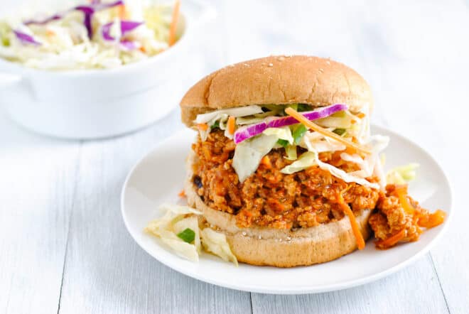Wheat hamburger bun filled with saucy chicken mixture and shredded vegetables.