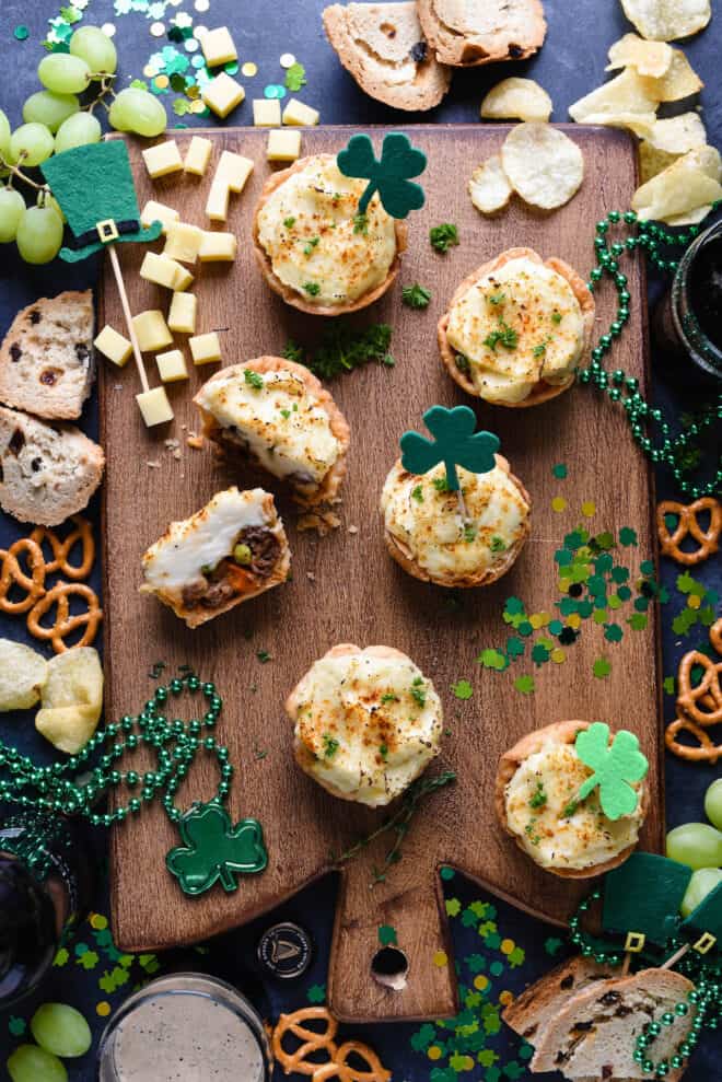 Festive St. Patrick's Day party scene with mini shepherd's pie, confetti, beads, pretzels, chips and beer.