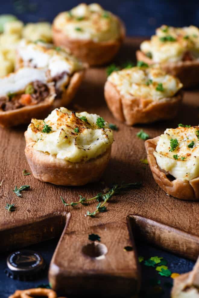 Mini shepherd's pie muffins on cutting board with thyme.