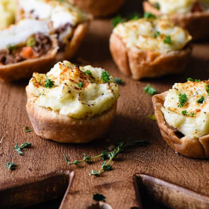 Mini shepherd's pie muffins on cutting board with thyme.
