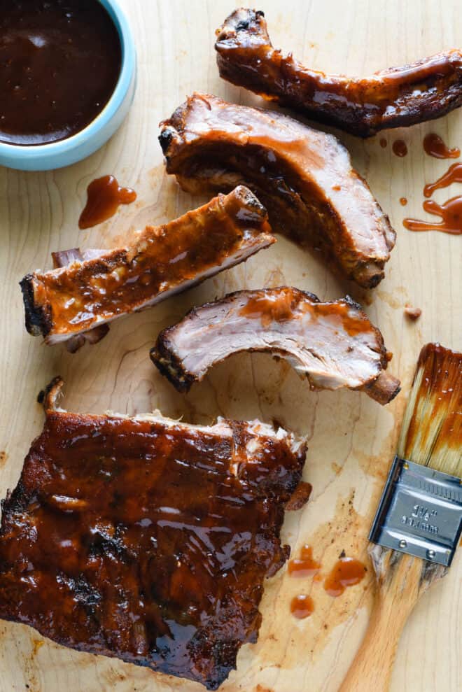 Closeup on wooden cutting board with cut up crock pot baby back ribs.