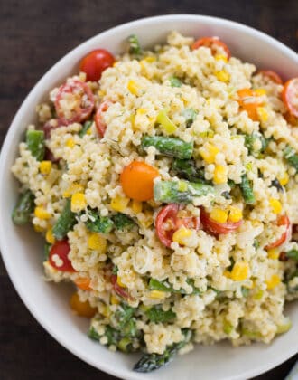 White bowl filled with acini di pepe pasta salad with tomatoes, asparagus and corn.