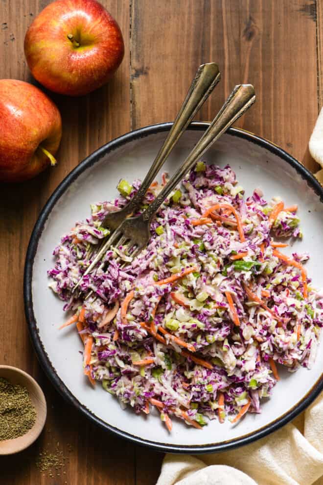 Shredded cabbage and carrots tossed with easy coleslaw dressing, in a shallow white bowl with a blue rim.