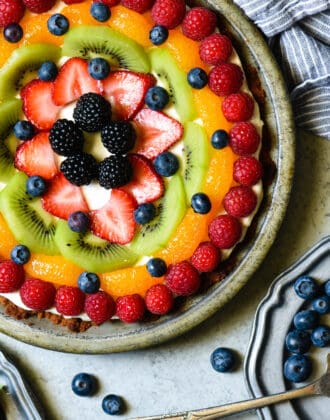 Frozen yogurt pie topped with artfully arranged fruit on a light gray background.