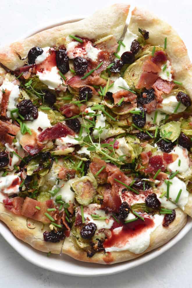 A rustic looking pizza, with Brussels sprouts on pizza, along with bacon, herbs and cherry glaze.