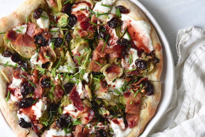 A rustic looking pizza, with Brussels sprouts on pizza, along with bacon, herbs and cherry glaze.