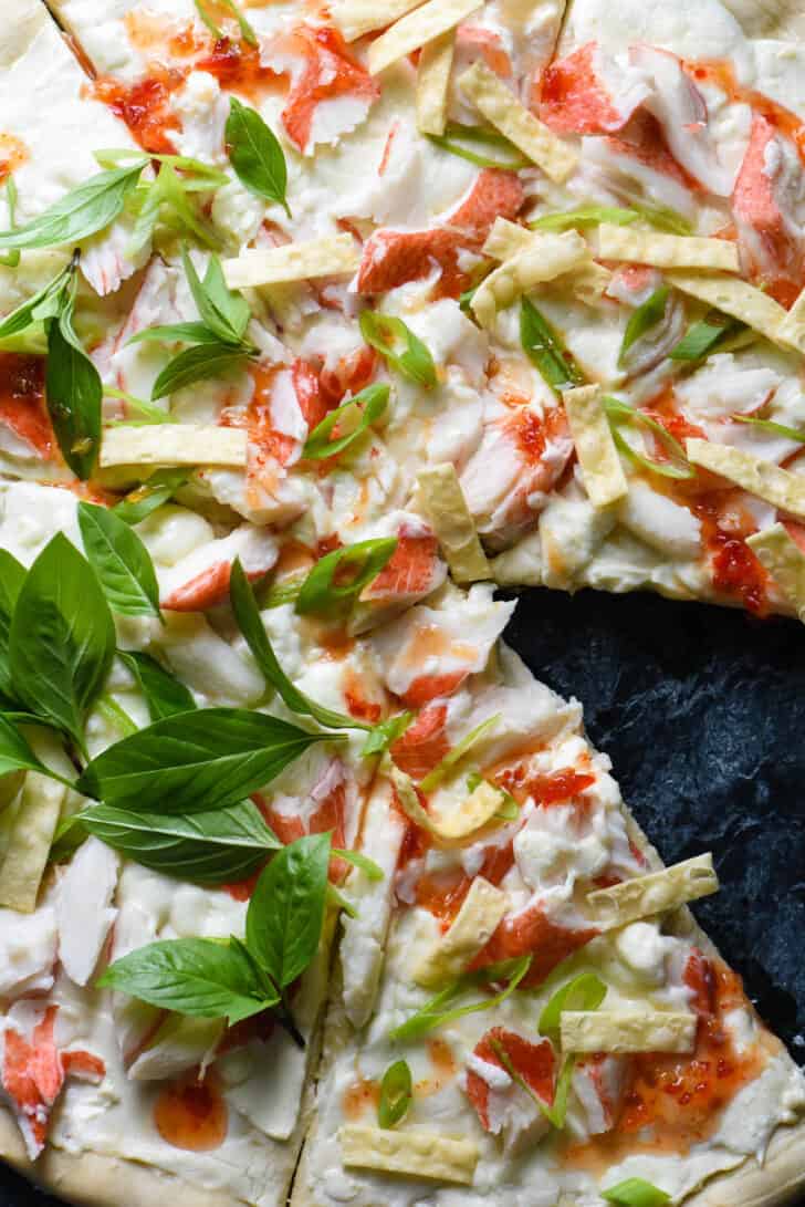 Pizza crust topped with cream cheese, imitation crab, green onions, wonton strips and basil.