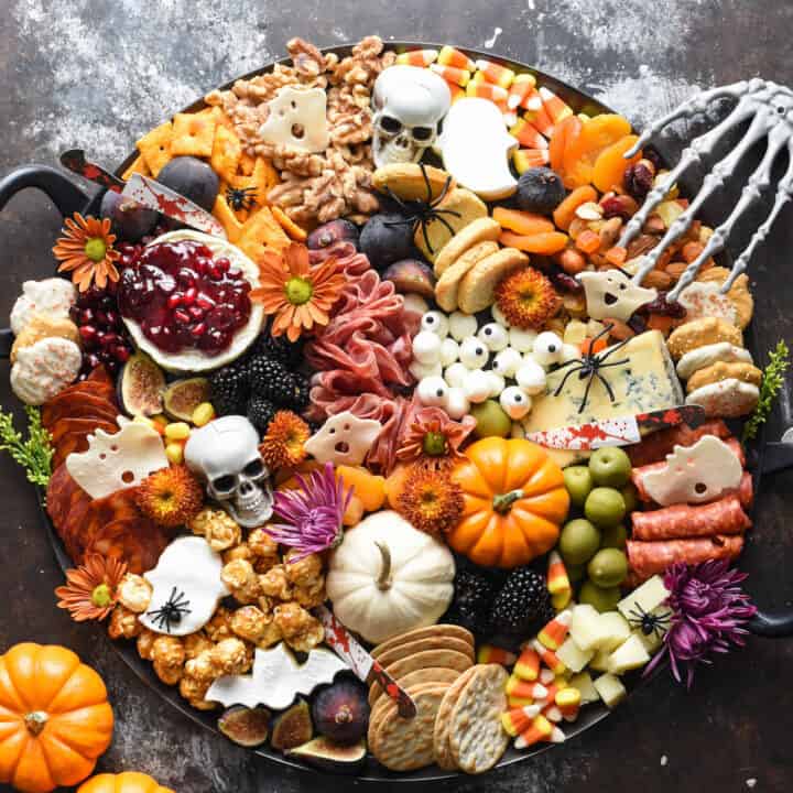 Halloween charcuterie board filled with cheeses, meats, pumpkins, crackers, nuts, fruits and sweets.