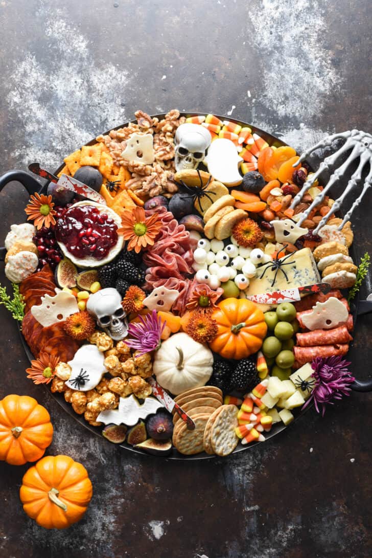 Halloween charcuterie board filled with cheeses, meats, pumpkins, crackers, nuts, fruits and sweets.