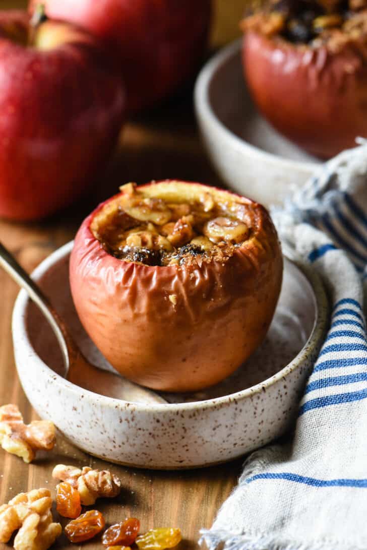 A small rustic dish with a walnut stuffed baked apple in it.