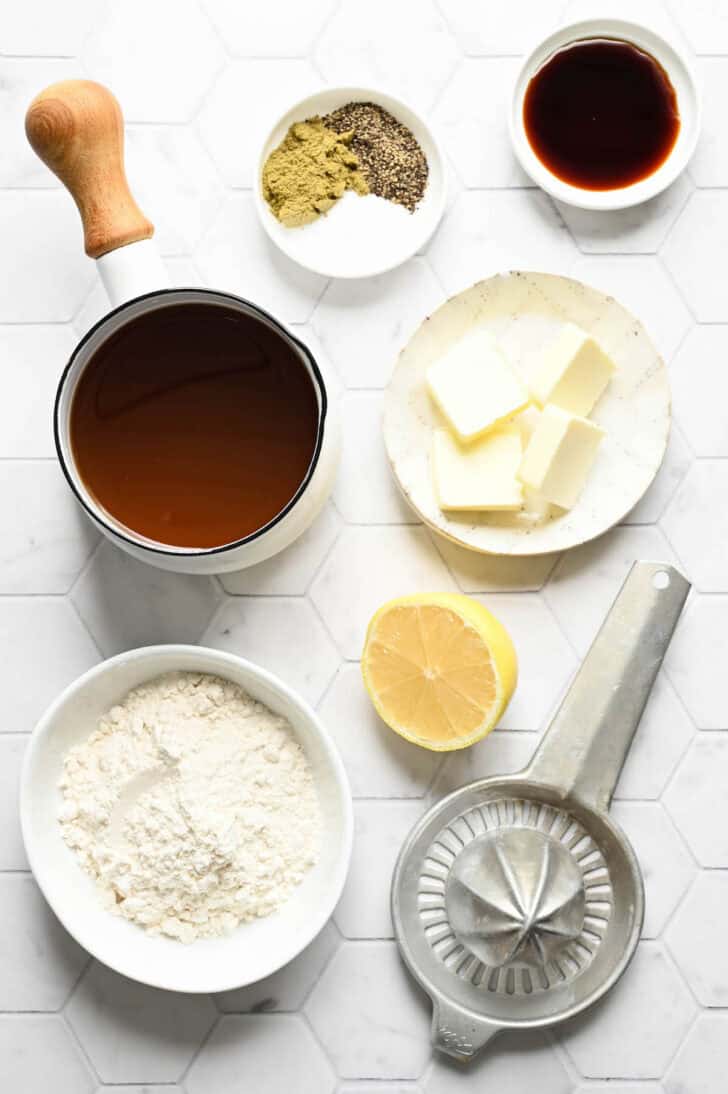 Ingredients on a tile surface, including butter, flour, broth, lemon, soy sauce and spices.