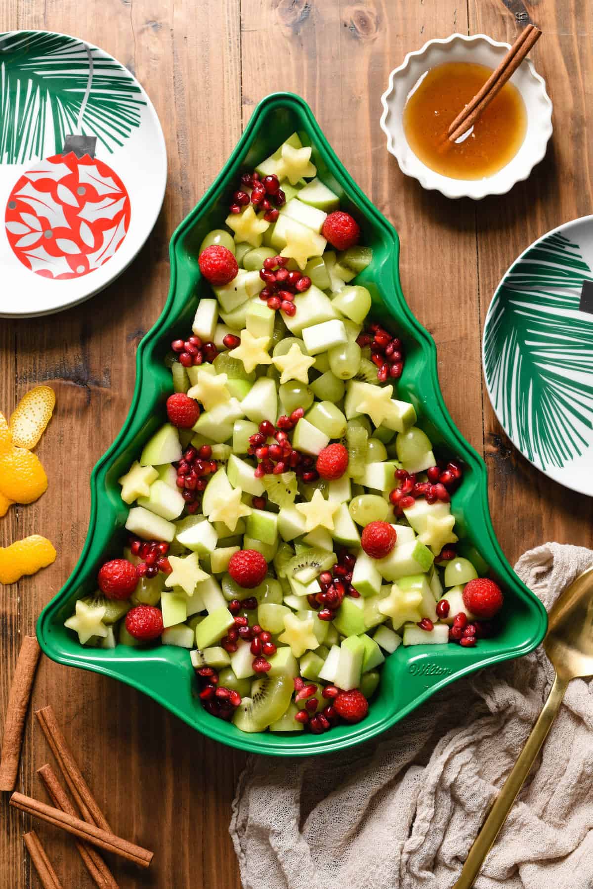 Christmas fruit salad made with grapes, raspberries, pomegranate seeds, kiwi, pineapple and green apple, arranged in a green Christmas tree shaped baking pan.