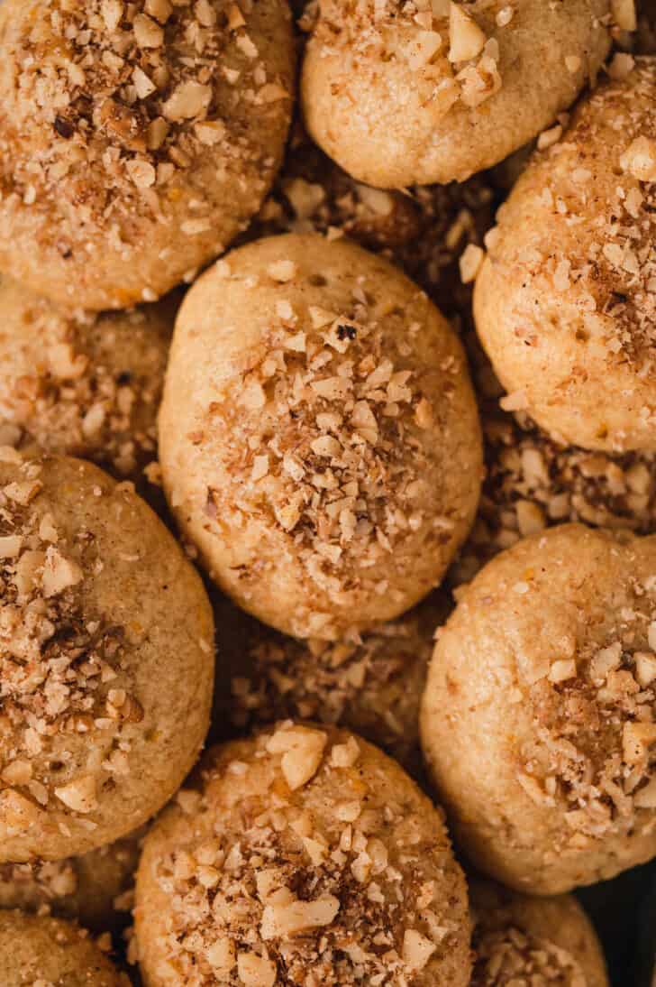 A closeup on melomakarona sprinkled with walnuts.