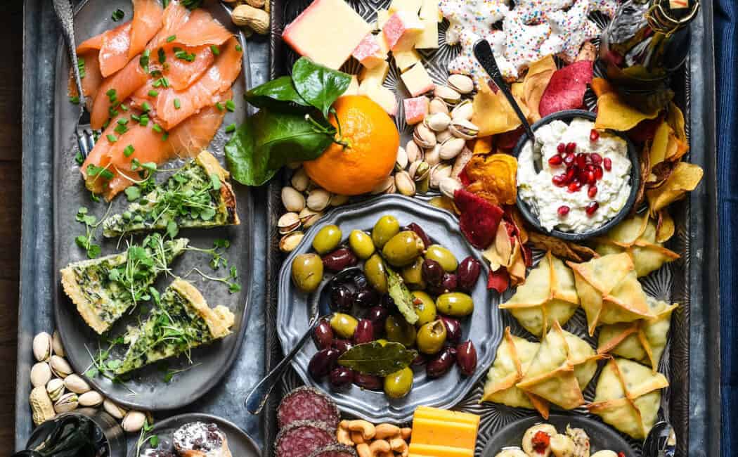 Platter filled with New Year's appetizers, including shrimp, cheese, cookies, wontons, cannoli and quiche.