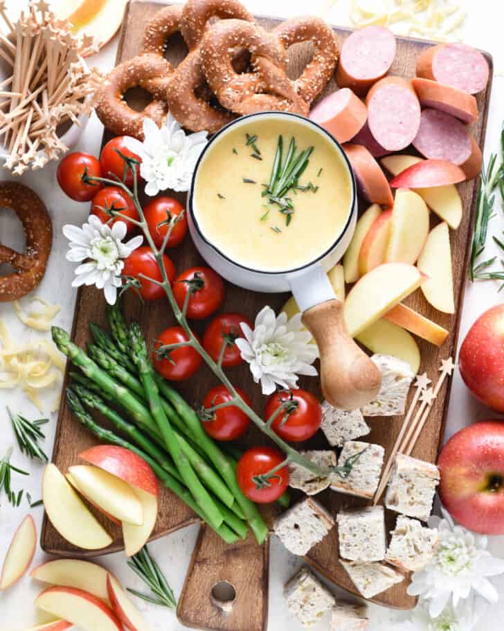 Food board ideas including cheese fondue, smoked sausage, veggies, bread, pretzels and apples.