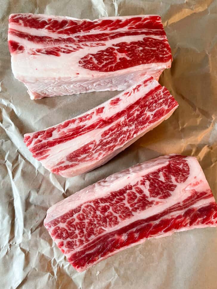 Raw beef short ribs on brown butcher paper.