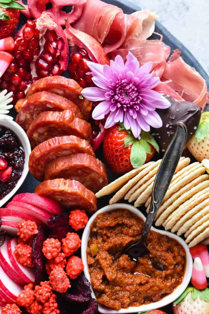 A platter filled with Valentine snack ideas including crackers, charcuterie, fruits and vegetables.