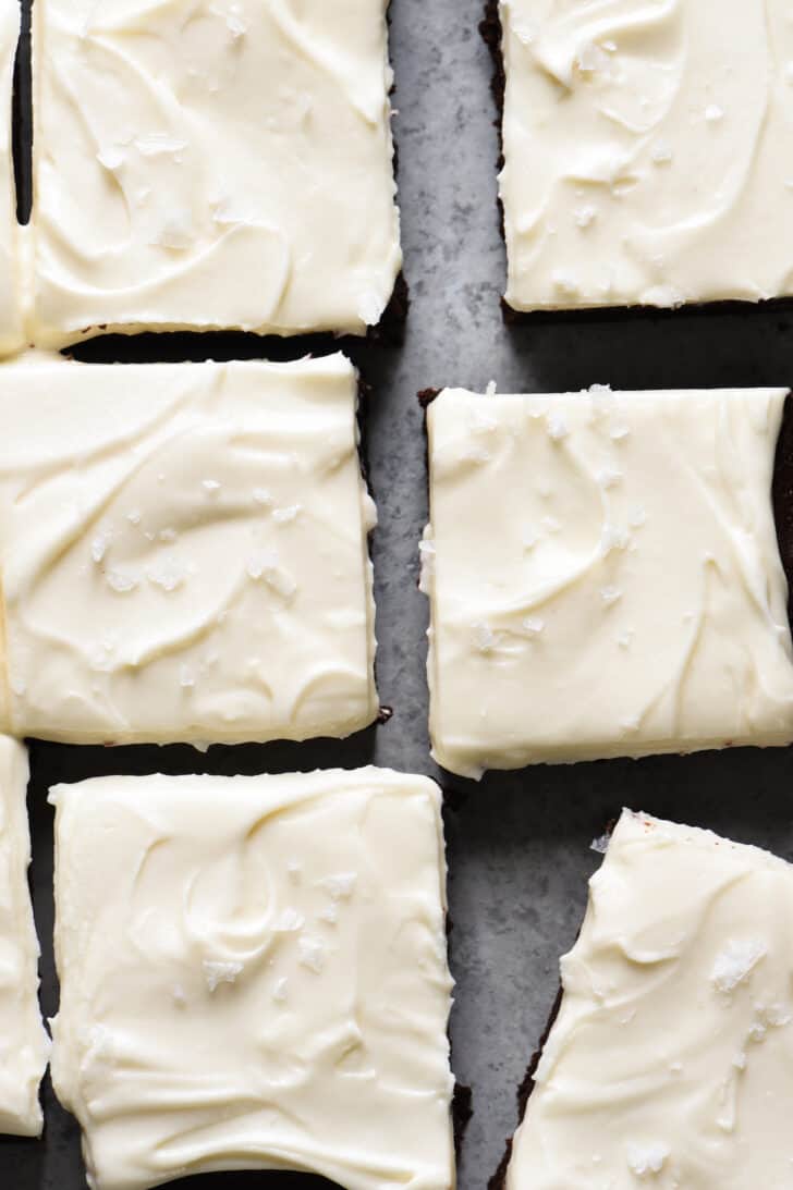 Baileys brownies with cream cheese frosting, cut into squares, on a grey surface.