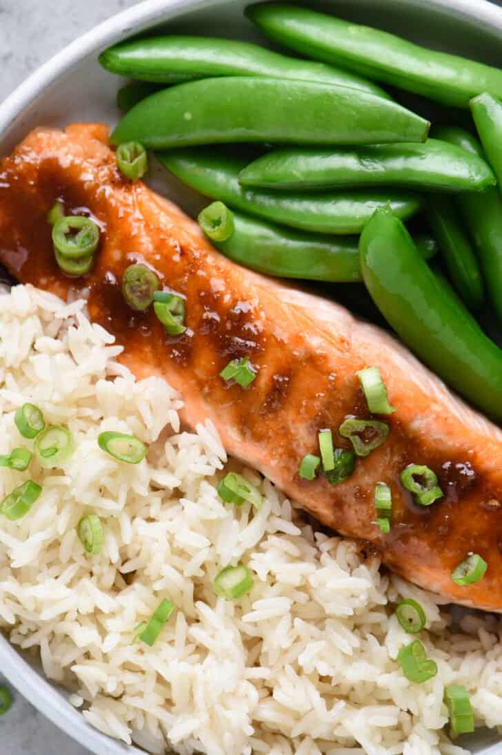 Closeup on plate of bourbon glazed salmon, white rice and sugar snap peas.