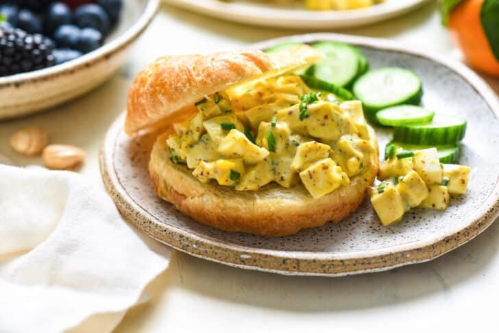 Rustic plate with a croissant filled with pickled egg salad.