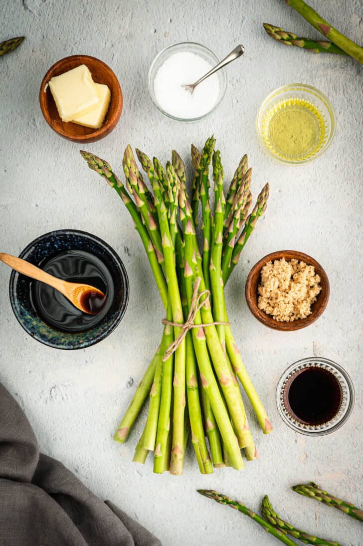 Ingredients on a light surface, including asparagus, balsamic vinegar, butter, brown sugar and soy sauce.