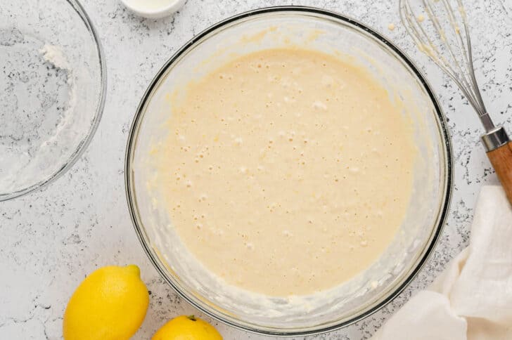 A glass mixing bowl filled with lemon pancake batter.