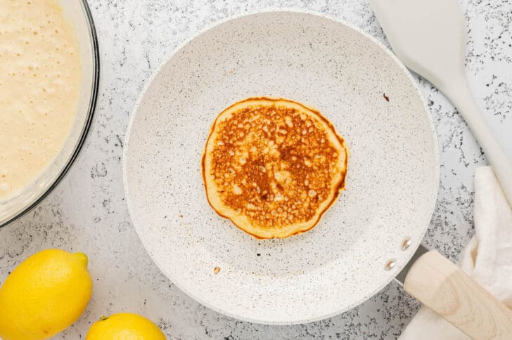 A light colored skillet with a lemon pancake in it.