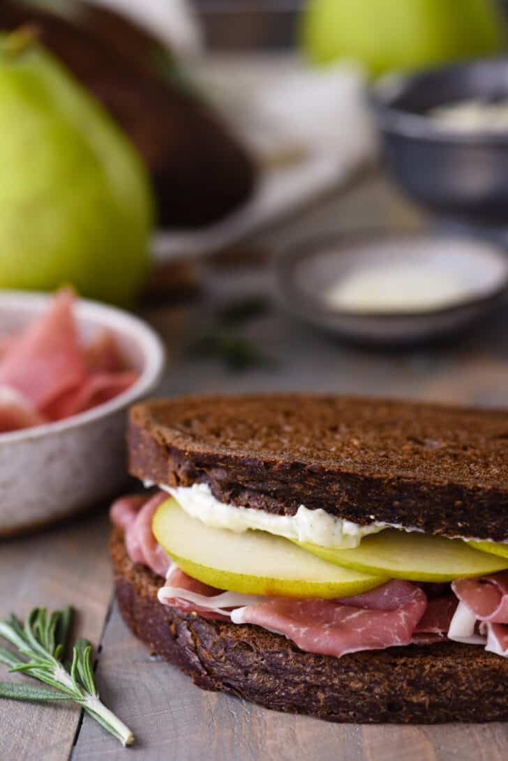 Pumpernickel bread sandwich filled with prosciutto, sliced pears and mayo.