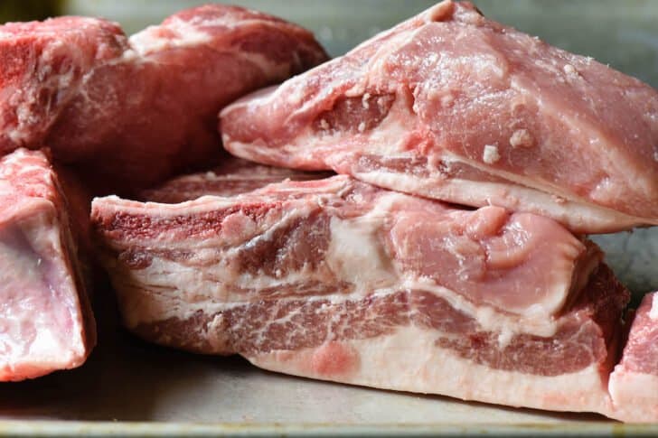 Raw pork bones with meat on a metal sheet pan.