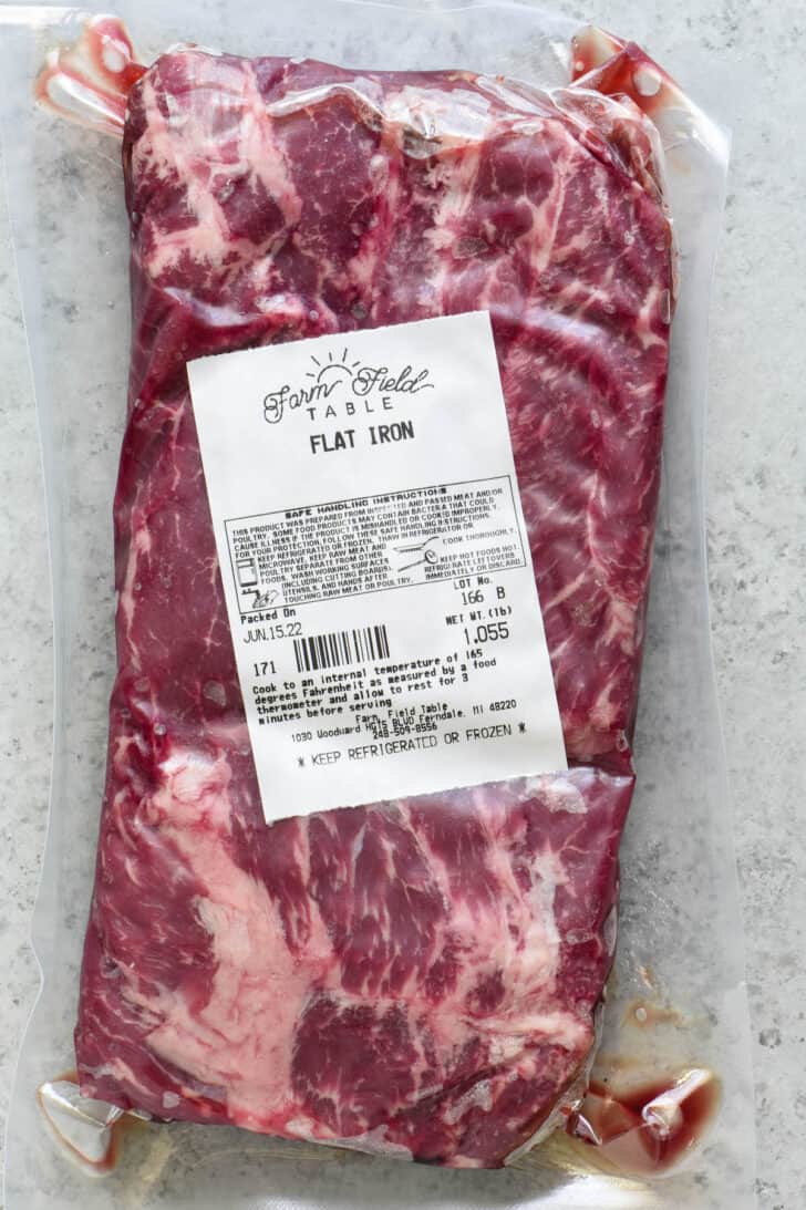 A plastic wrapped flat iron steak with a butcher's sticker on it.