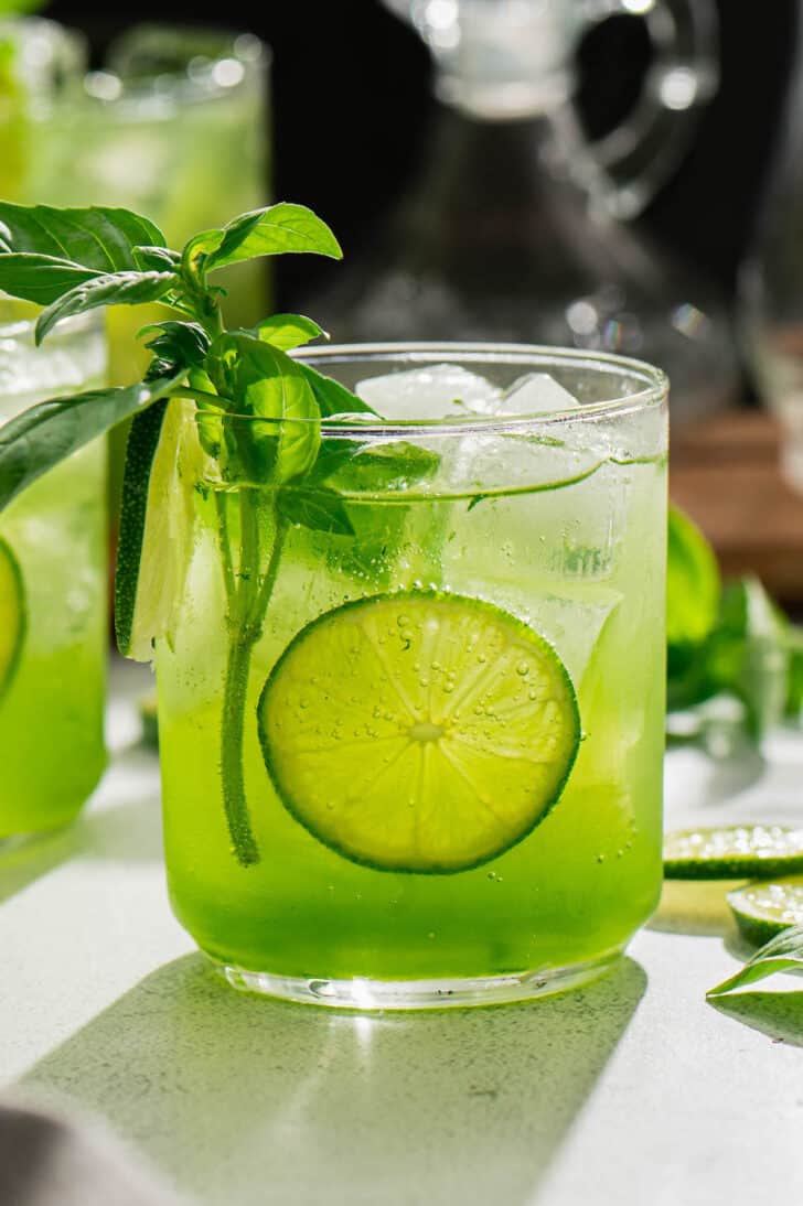 Bright green hued basil cocktail garnished with a round of lemon.