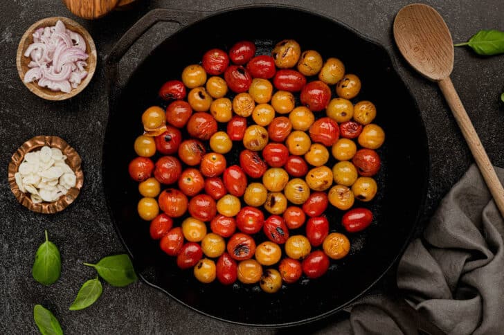 Blistered red and yellow tomatoes in a cast iron skillet.