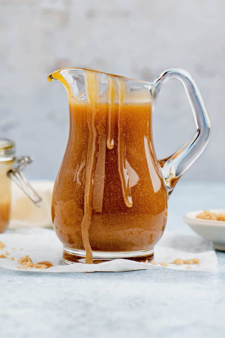 A small glass pitcher overflowing with quick caramel sauce.