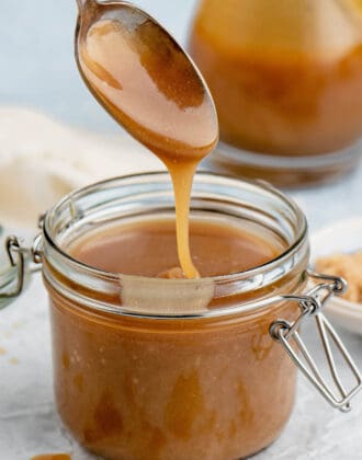 A spoon drizzling microwave caramel sauce into a small glass jar.