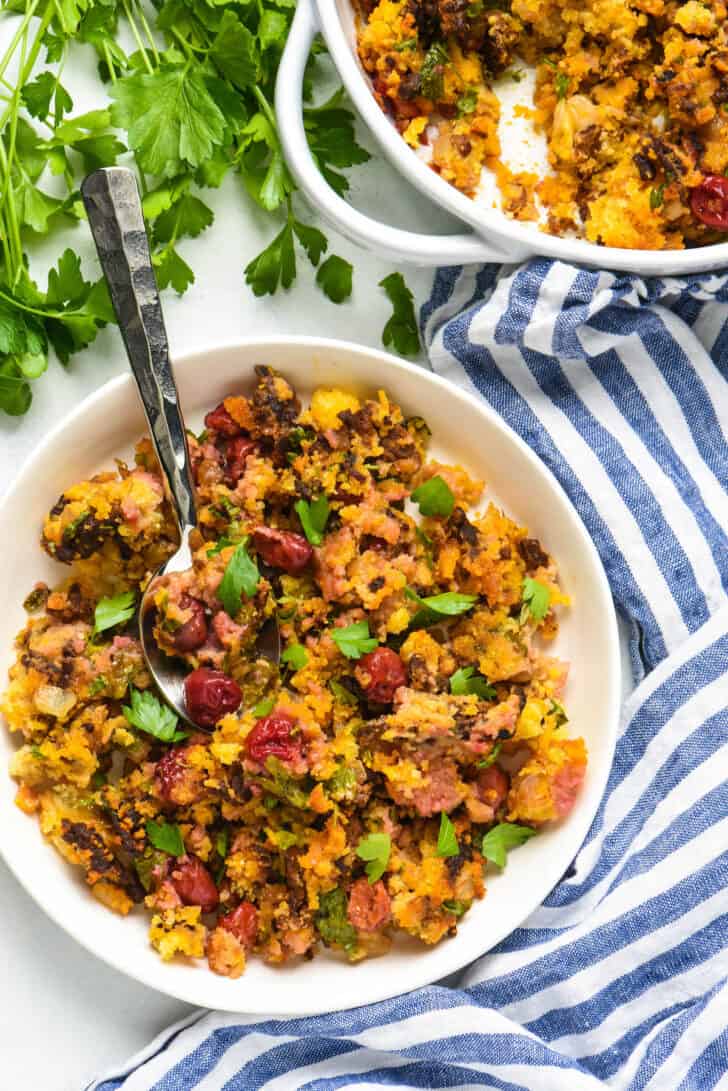 A white bowl filled with chorizo stuffing made with cornbread and tart cherries, Latin Thanksgiving recipes