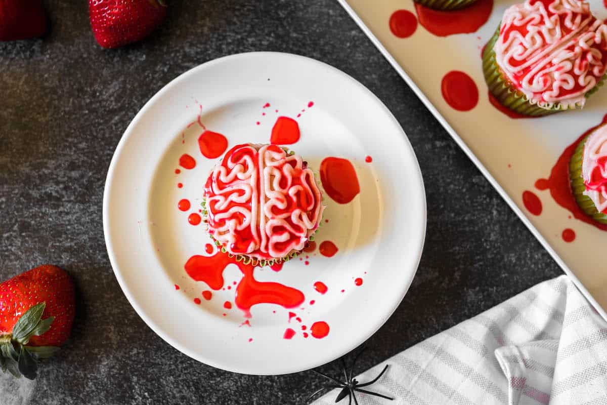 A Halloween cupcakes recipe piped with frosting to look like a bloody zombie brain, on a white plate.