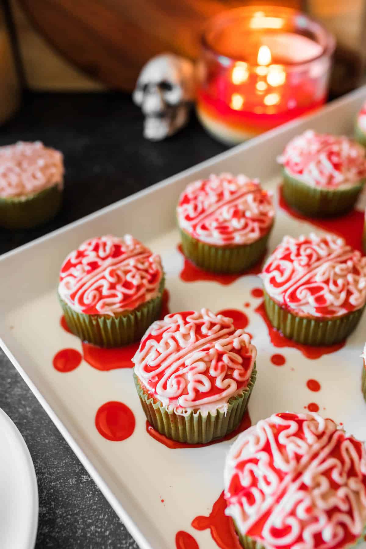 Halloween themed cupcakes piped with frosting to look like bloody zombie brains, on a white platter.