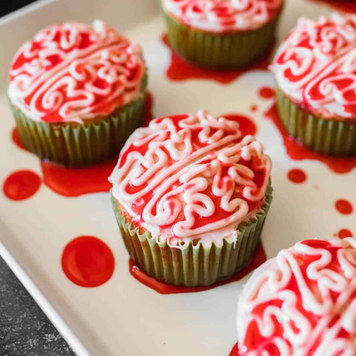 Halloween cupcakes piped with frosting to look like bloody zombie brains, on a white platter.