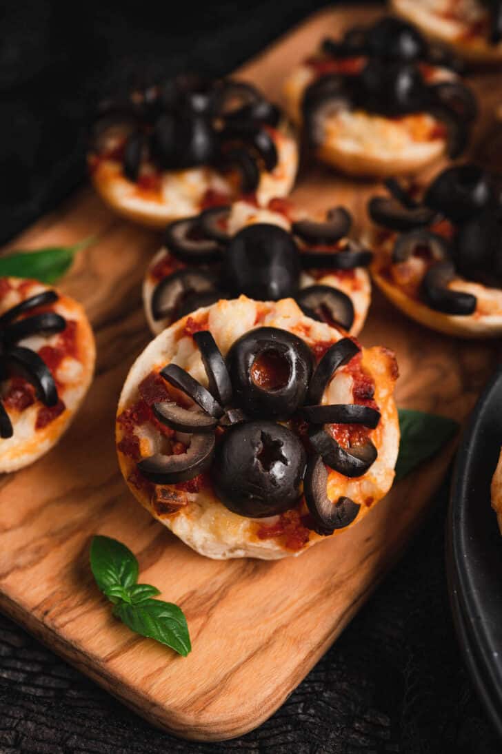 A Halloween pizza idea, made with mini pizza bagels and black olives.