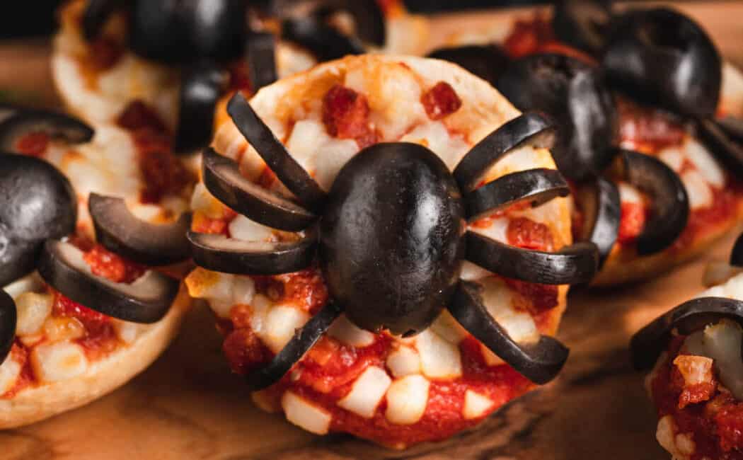 Halloween pizzas made with mini frozen pizza bagels and black olives cut to look like spiders.