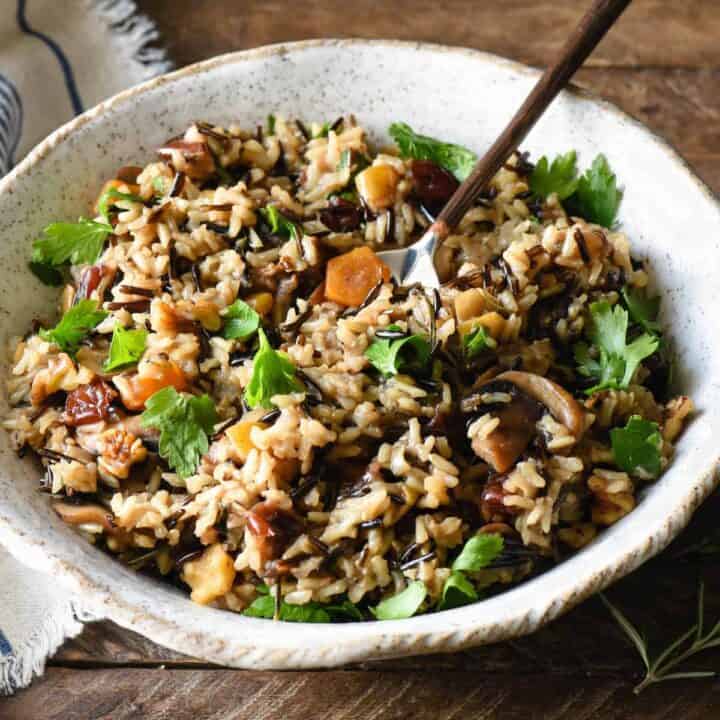 Thanksgiving rice pilaf in handmade pottery bowl with spoon in it.