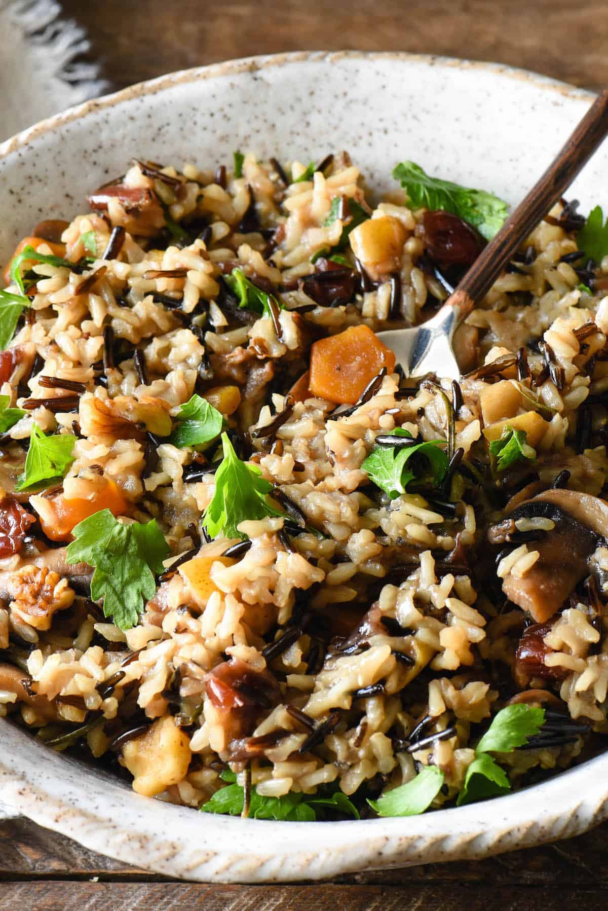 Wild grain and vegetable side dish in handmade pottery bowl with spoon in it.