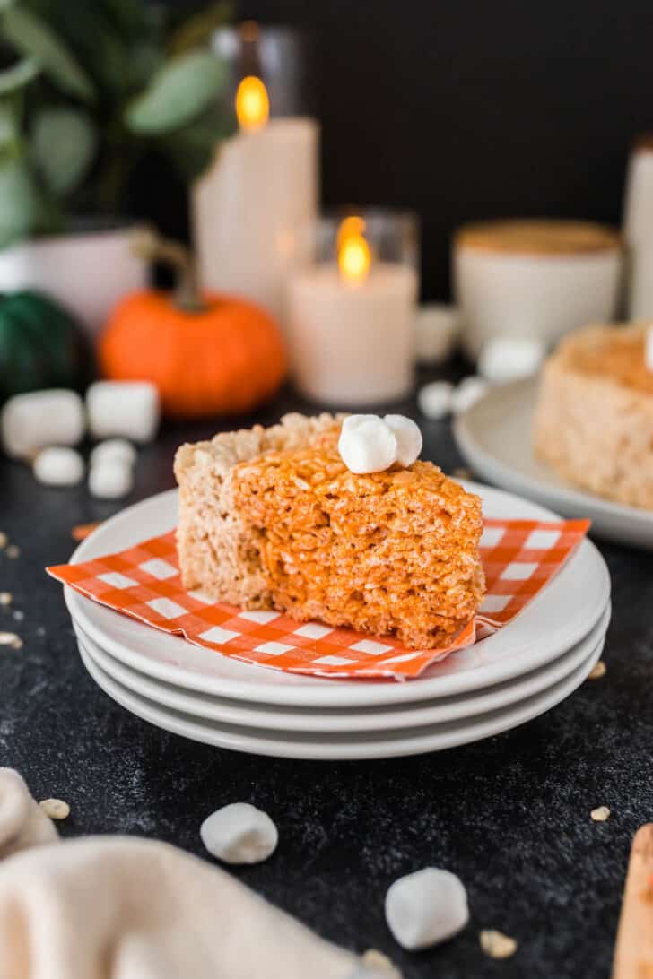 A slice of orange Thanksgiving Rice Krispies treats, shaped like a pie, on a white plate with an orange and white napkin.