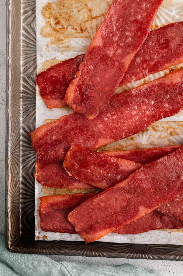 Oven baked turkey bacon slices sitting on top of a rimmed baking pan.