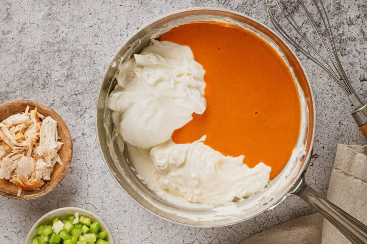 A saucepan filled with cream cheese, Greek yogurt and buffalo sauce.