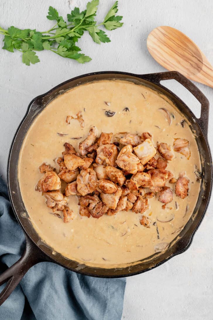 Sauteed chicken on top of a creamy mushroom sauce in a cast iron skillet.