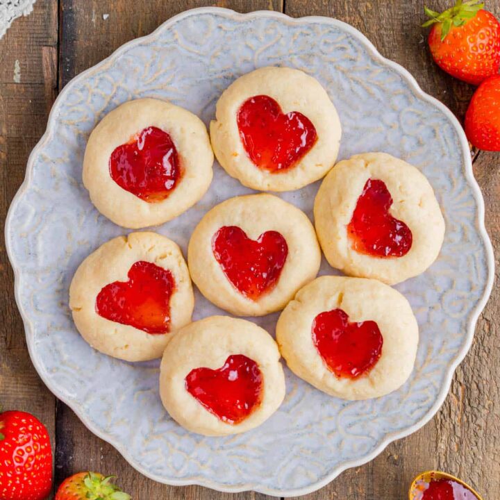 Heart jam cookies made with shortbread and strawberry jam, on a decorative plate.