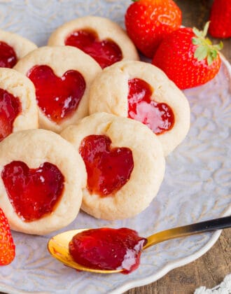 Heart jam cookies made with shortbread and strawberry jam, on a decorative plate.
