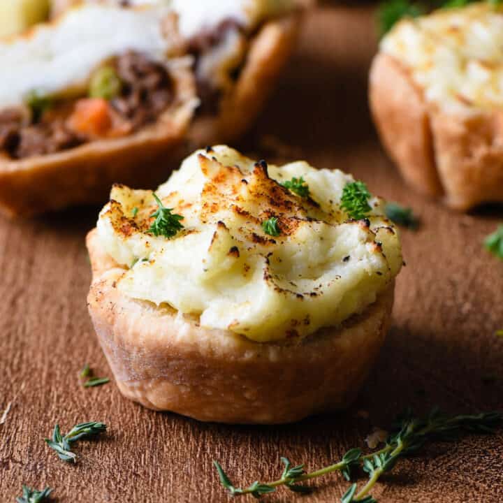 Mini shepherd's pie muffins on cutting board with thyme.